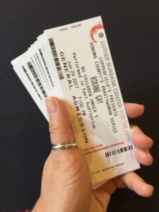 A hand holding a fanned out stack of tickets for Roxanne Gay at the LBC
